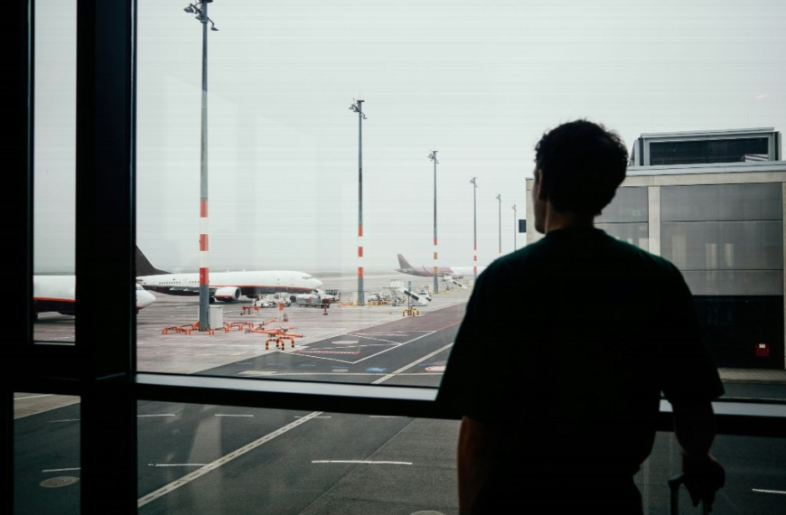 person looking out the window at an airport - Who Helps When a Loved One Passes Away Overseas